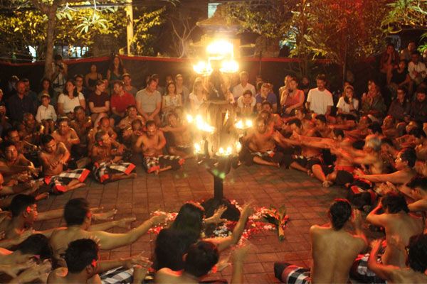 Un grupo de hombres cantan al unísono alrededor del fuego en la danza Kercak